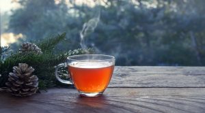 Cup with hot steaming tea on a rustic wooden garden table with C